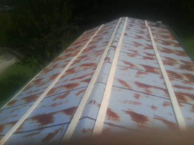 Rusted metal roof panels with new wood purlins before replacement in Julian