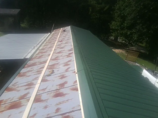 Old rusted panels beside newly installed green metal roofing — Wind Damage Roof Repair by Roofing Brothers in Julian
