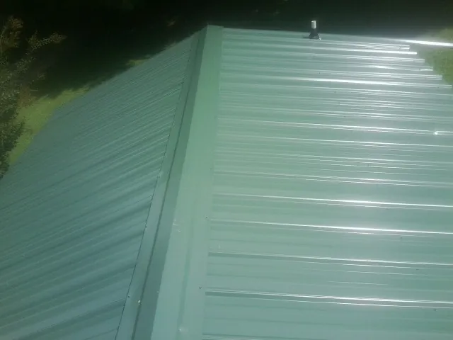 New green metal panels meeting at the ridge of a roof — Flat Roof Repair work by our crew in Julian